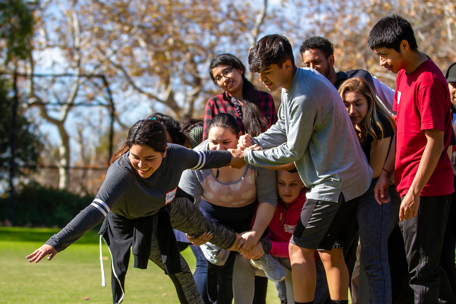 A group of high school students engaged in an active outdoor team-building exercise.