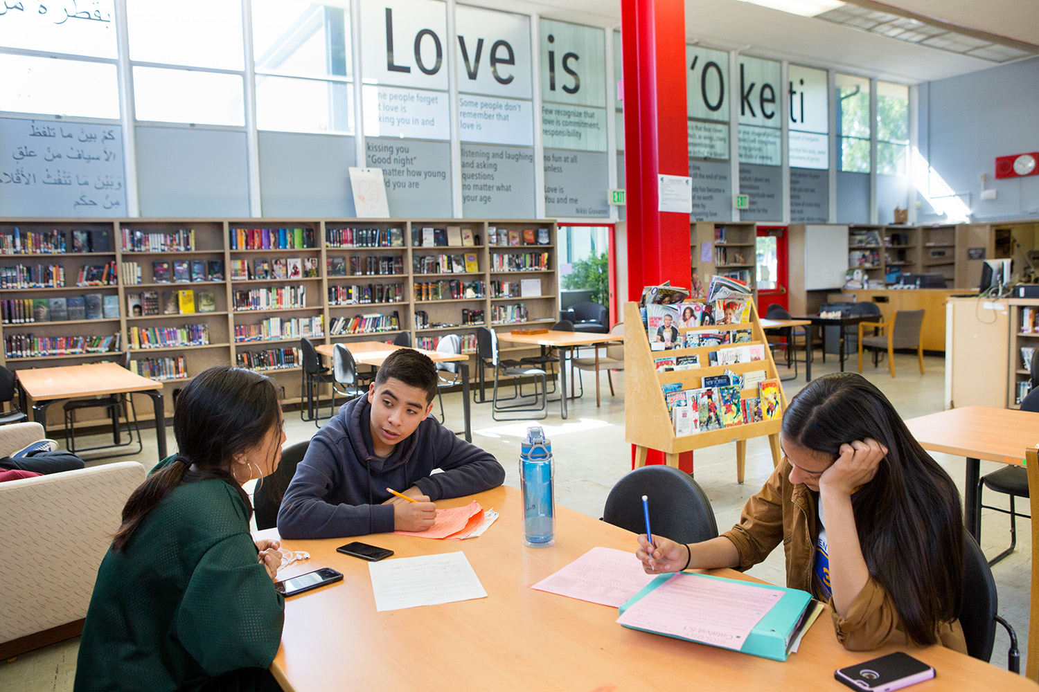 A small group of high school students work together on tutoring in a school library.